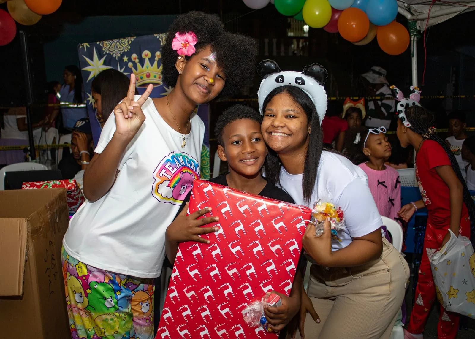 Una niña y dos mujeres posan junto a un regalo envuelto